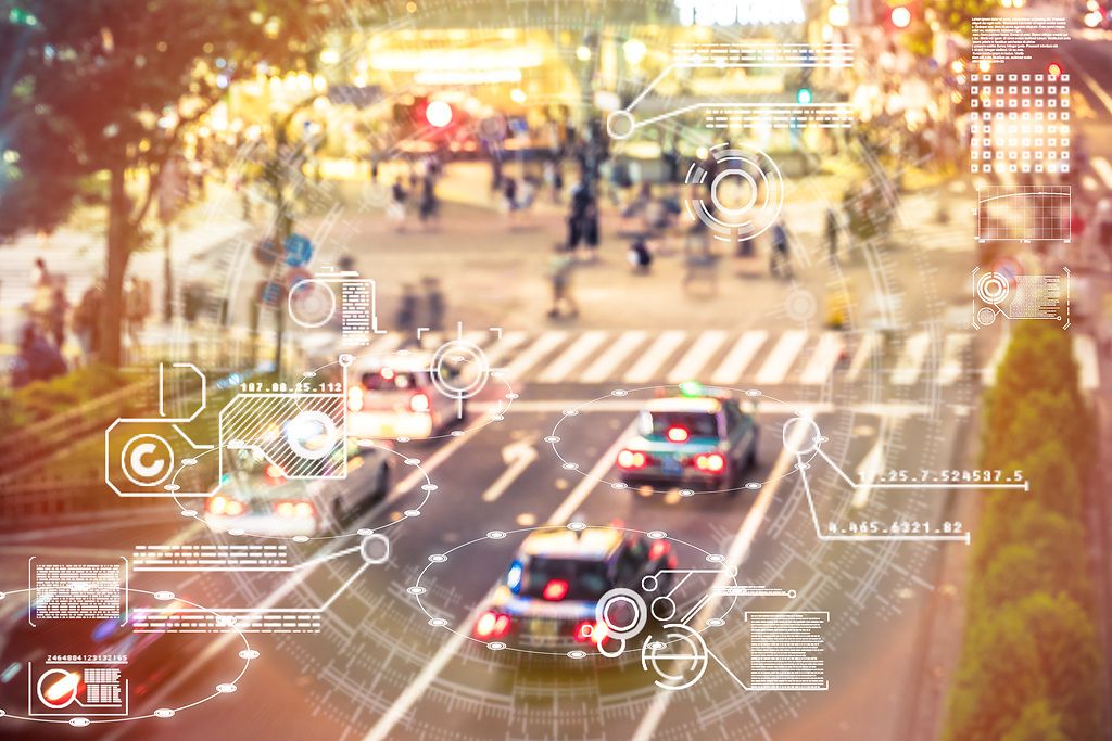 Verschwommenes Bild einer belebten Straße mit Autos und Menschen.