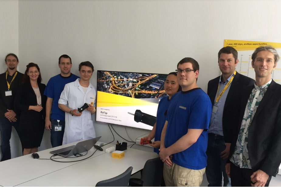 Eine Gruppe von Menschen steht vor einem großen Bildschirm.