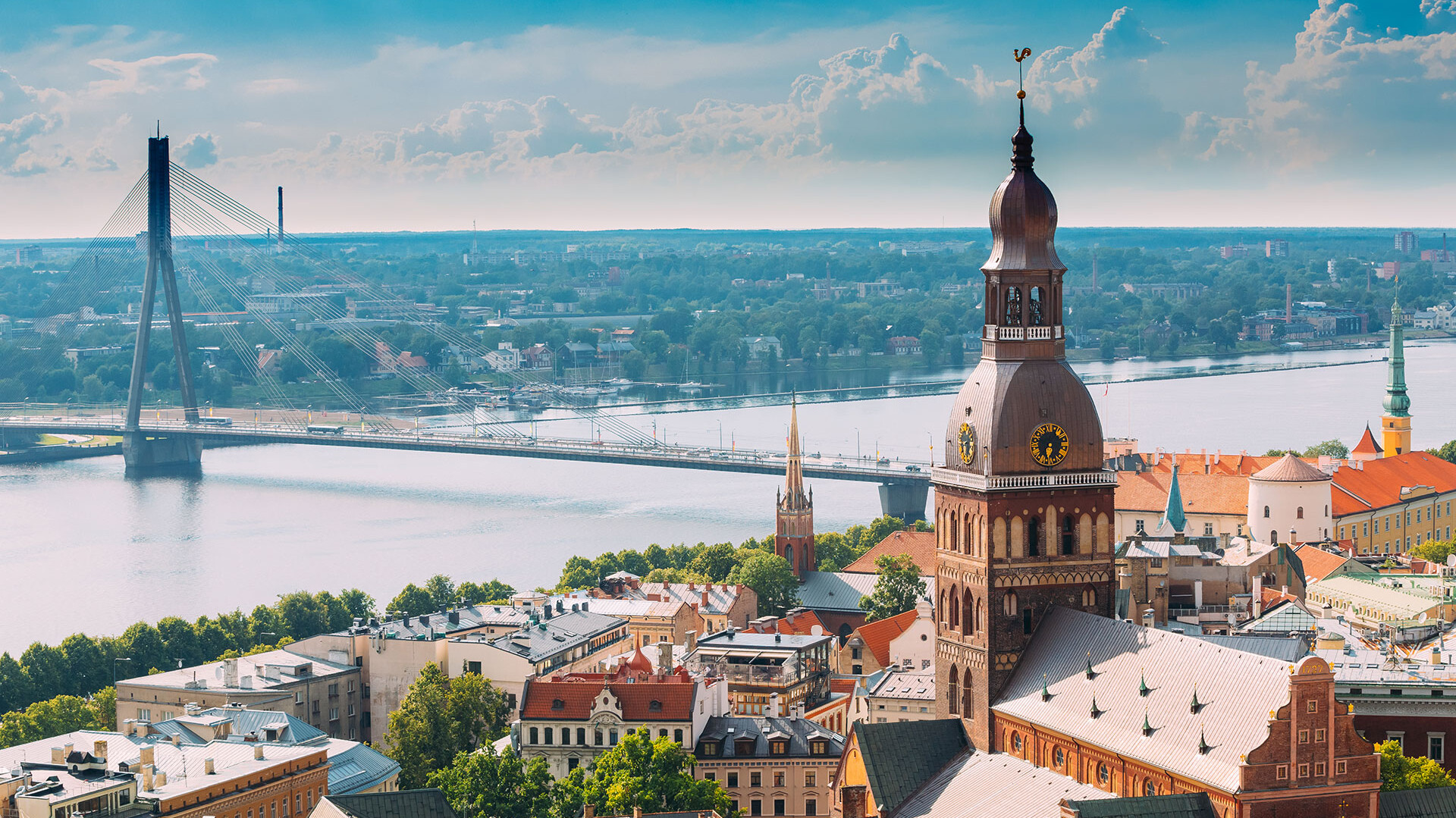 Stadt mit Fluss und Brücke im Vordergrund, bewölkter Himmel.