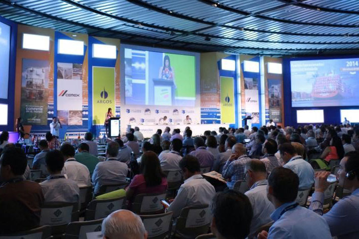 Eine Gruppe von Menschen sitzt in einem Konferenzsaal vor einem großen Bildschirm.