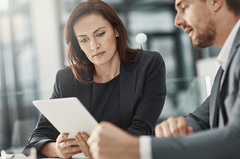 Una mujer mirando una tableta en un entorno de negocios.
