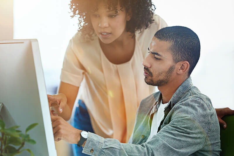 Un hombre y una mujer analizando un diagrama en una pizarra blanca en un entorno de oficina.
